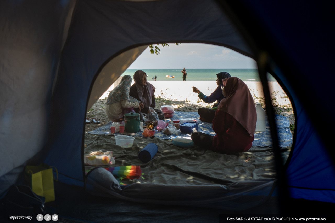 Sekumpulan pengujung sedang menjamu selera di Pantai Saujana, Port Dickson.