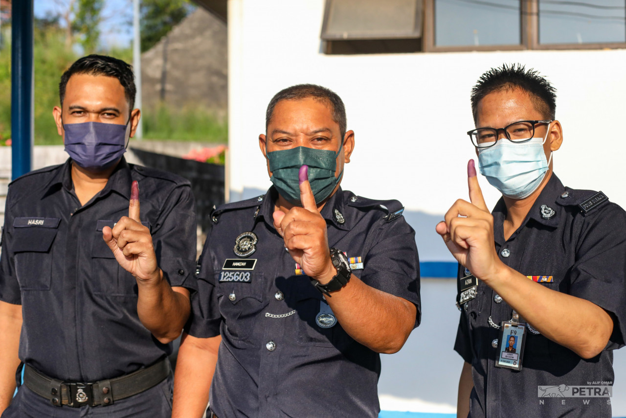 Para anggota polis yang selesai membuang undi awal menunjukkan jari yang telah disapu dakwat kekal. - Gambar oleh Alif Omar
