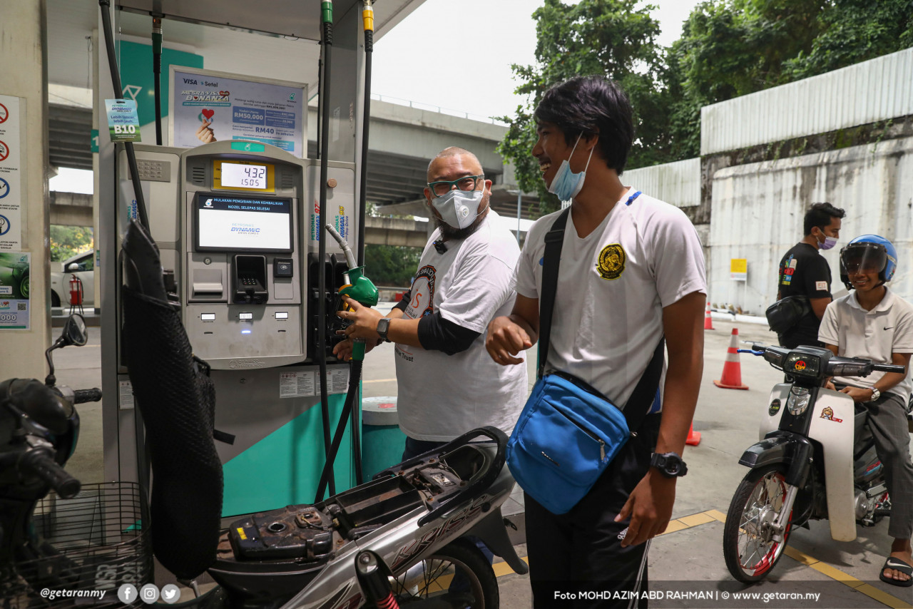 Afdlin Shauki membantu seorang penunggang motosikal mengisi minyak.