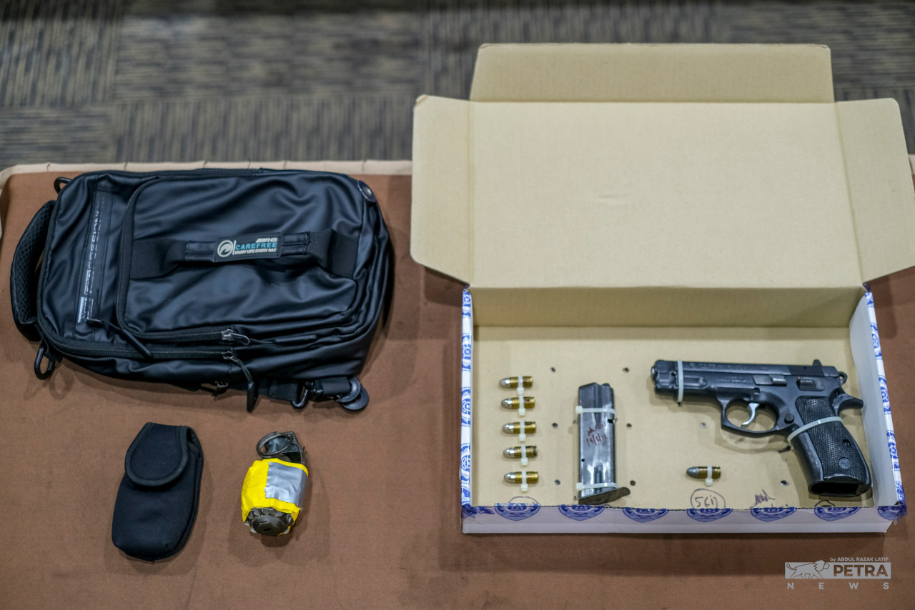 Bom tangan dan sepucuk pistol yang dirampas polis dalam serbuan. - Gambar oleh Abdul Razak Latif