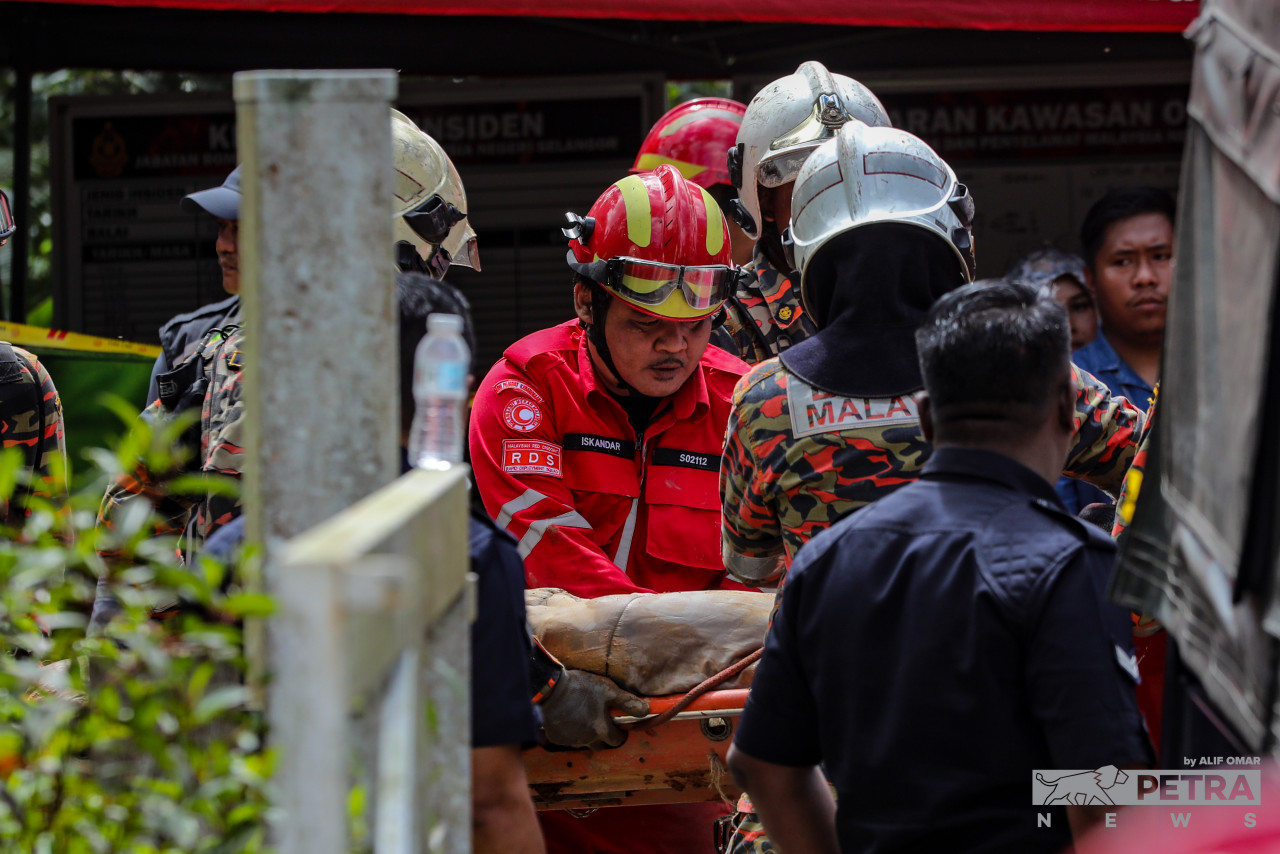 Mayat salah seorang mangsa tanah runtuh dibawa keluar dari lokasi kejadian, semalam.