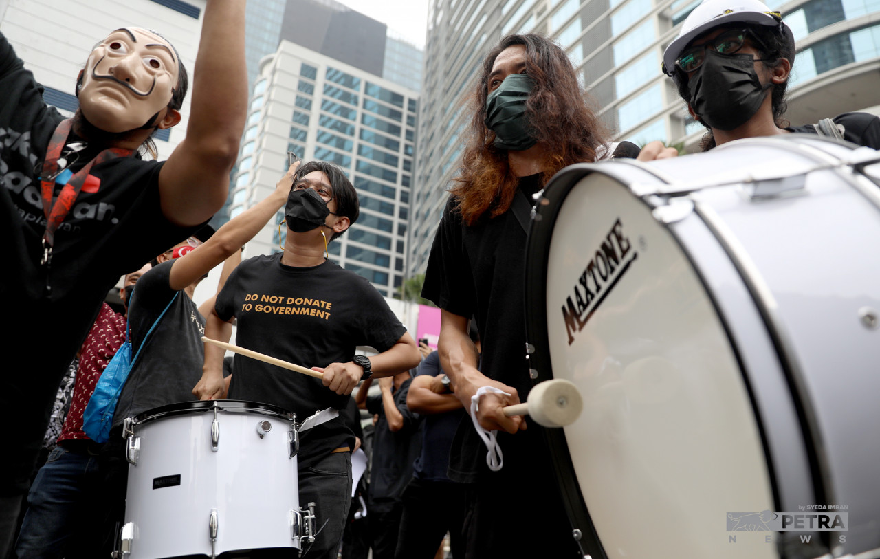 Adam Adli (tengah) memukul gendang ketika cuba berarak pada Perhimpunan #TangkapAzamBaki, hari ini.