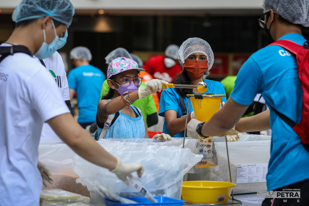 Sukarelawan membungkus pek makanan. - Gambar oleh Syeda Imran