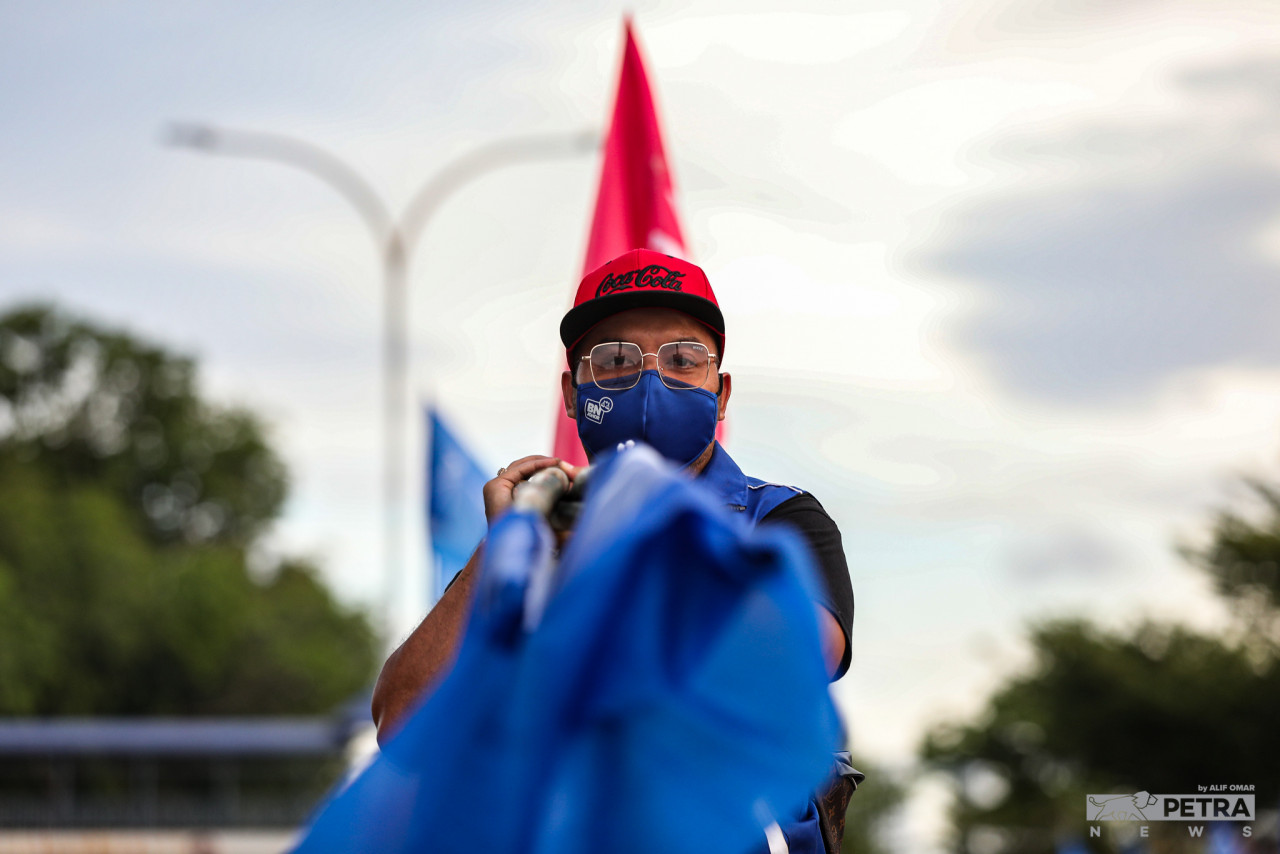 Seorang petugas parti BN mengusung bendera untuk dipacak di beberapa kawasan di DUN Johor Jaya.