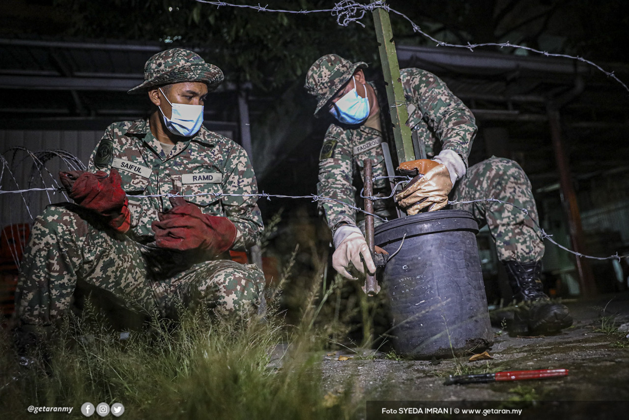 Dua anggota tentera memasang kawat berduri di Pangsapuri Permai.