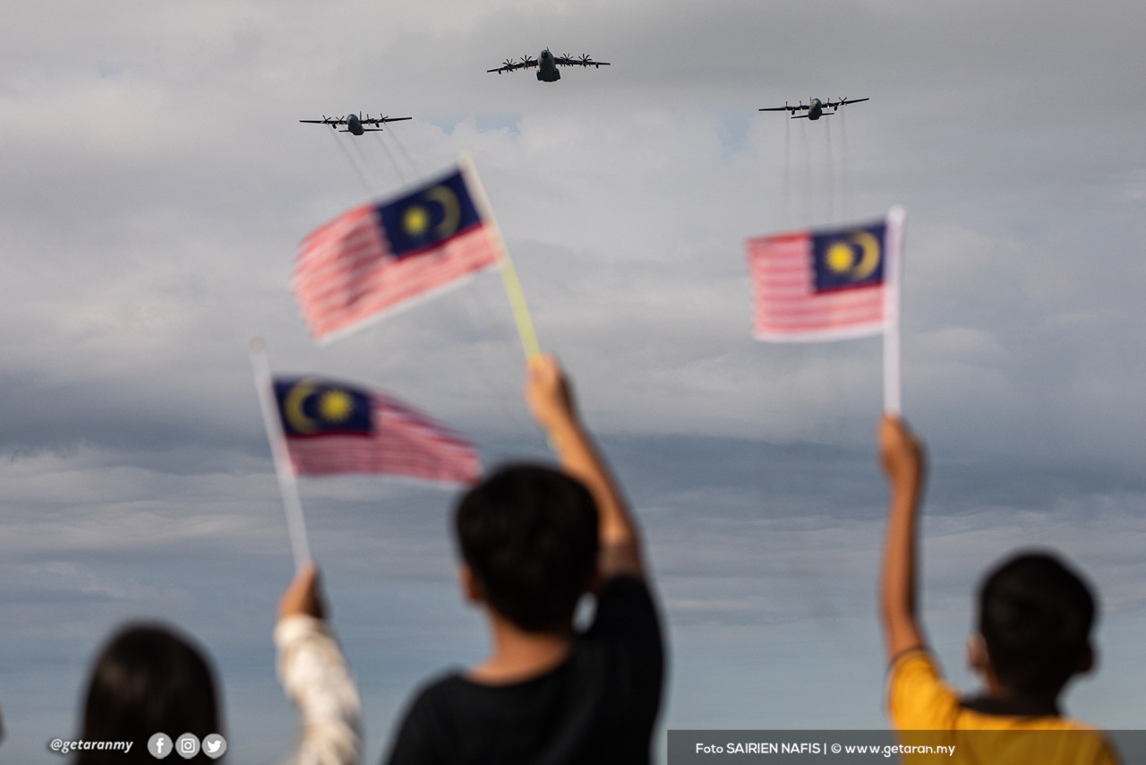 Sekumpulan kanak-kanak mengibarkan Jalur Gemilang kepada pesawat TUDM yang membuat persembahan udara. - Gambar oleh Sairien Nafis