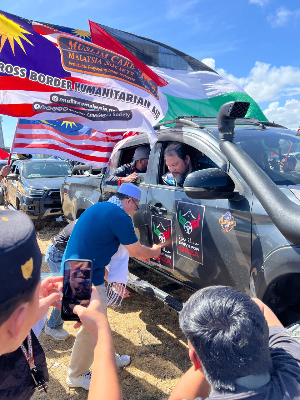Hishamuddin Abdul Karim melekatkan poster kempen pada 4x4 seorang peserta