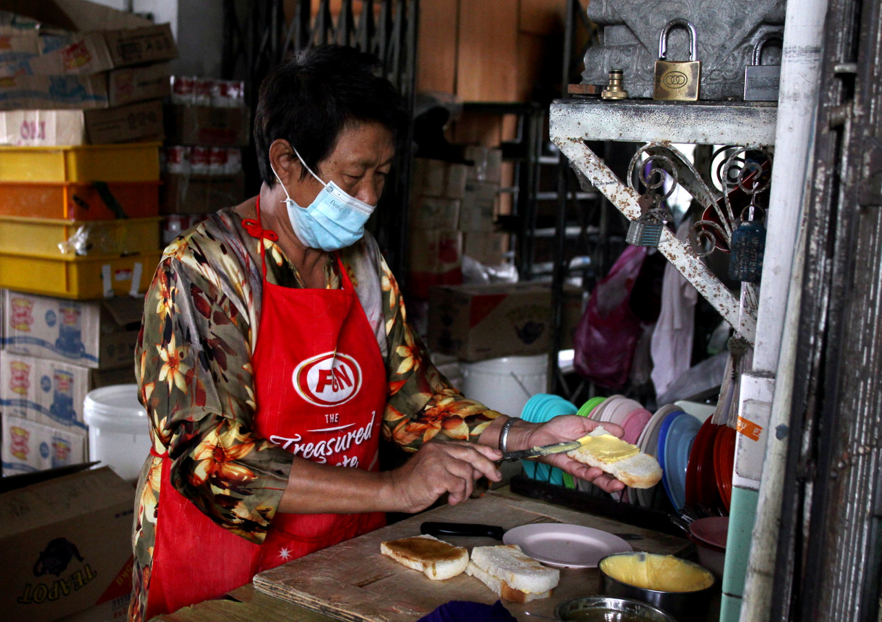 Ah Ling, 55, menyediakan roti ban bakar yang disapukan dengan marjerin dan kaya untuk pelanggan Restoran Double Lion, Kuala Kangar ketika ditemui baru-baru ini. - Gambar Bernama