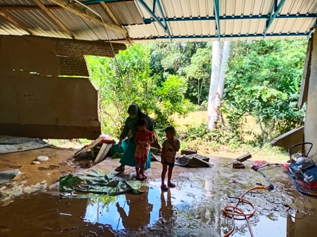 Nani Kartina Abdul Razak, 42, membersihkan rumahnya yang dilanda banjir kilat hingga menyebabkan dinding ruang tamu runtuh di Kampung Landai, Gulau, malam tadi.