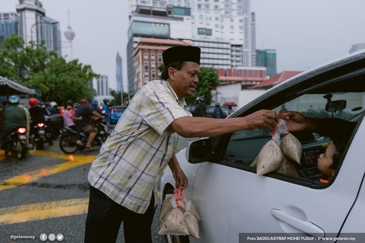 Seorang sukarelawan masjid mengagihkan bubur lambuk. - Gambar fail