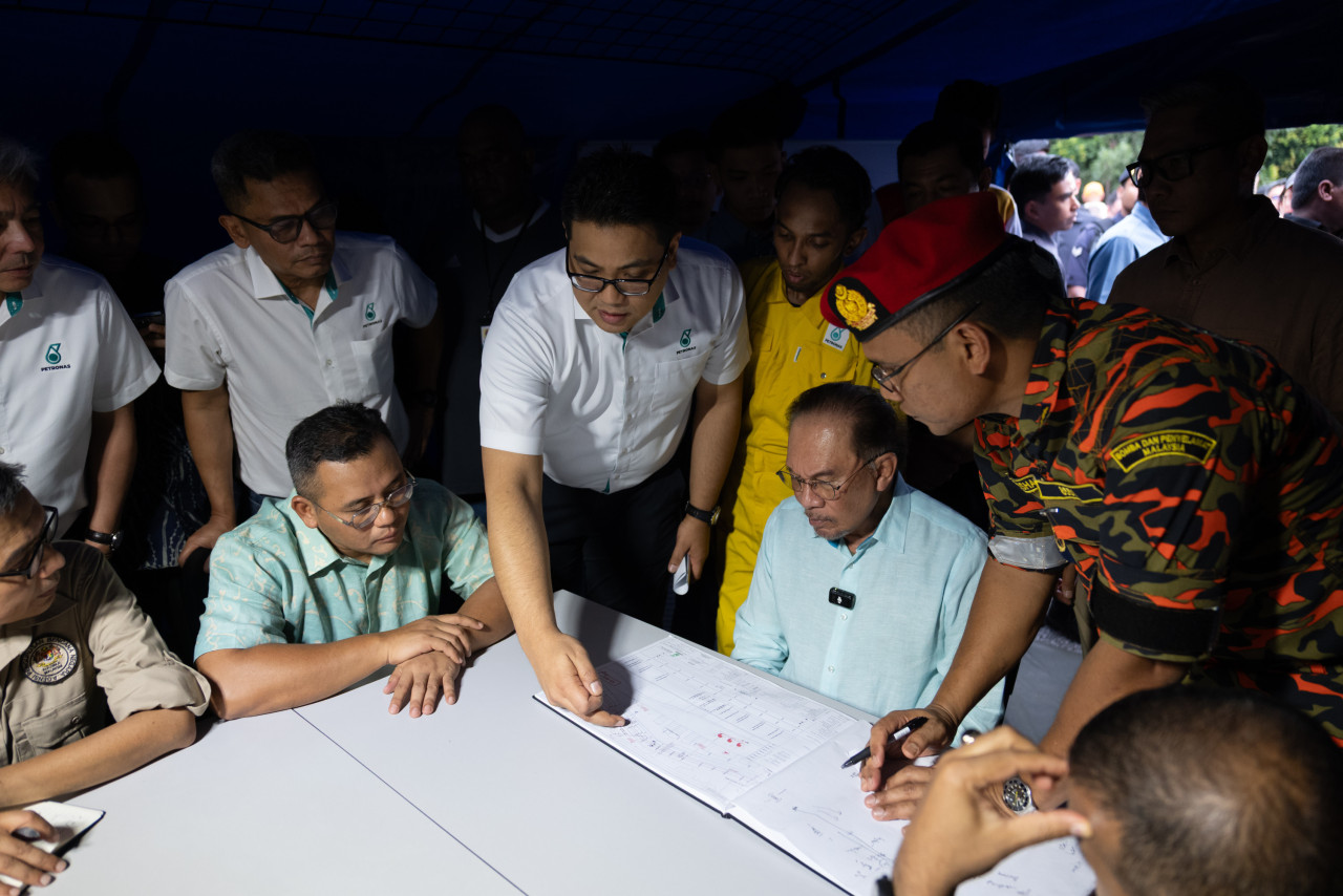 Anwar Ibrahim (duduk, kanan) dan Amirudin Shari (duduk, dua kiri) mendengar taklimat ketika tinjauan ke kawasan kebakaran saluran gas petang tadi - Gambar PMO