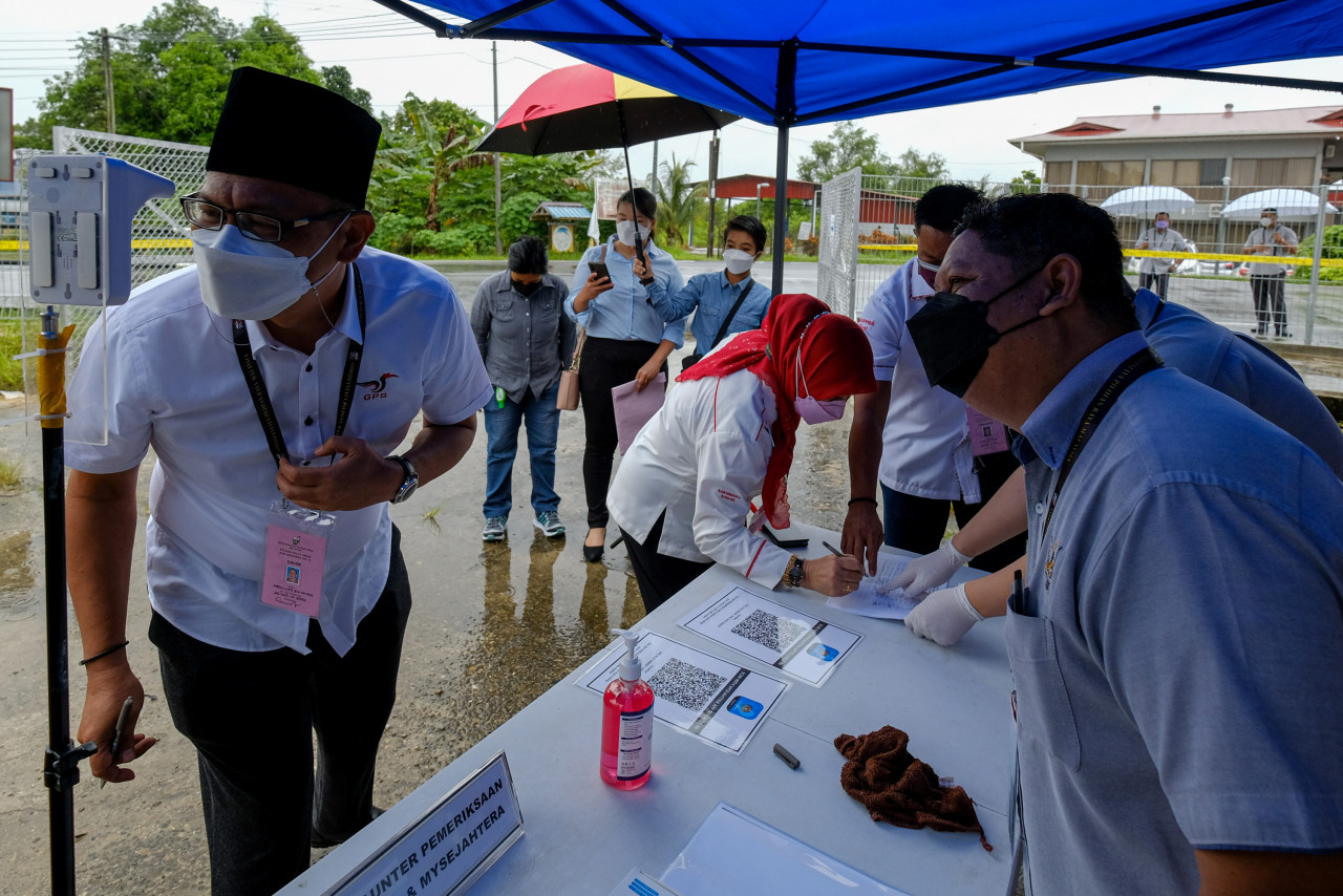 Calon GPS Datuk Abdullah Saidol melakukan imbasan suhu dan aplikasi MySejahtera ketika hadir di pusat penamaan calon DUN Semop di Dewan Serbaguna Pejabat Daerah Meradong hari ini. - Gambar Bernama
