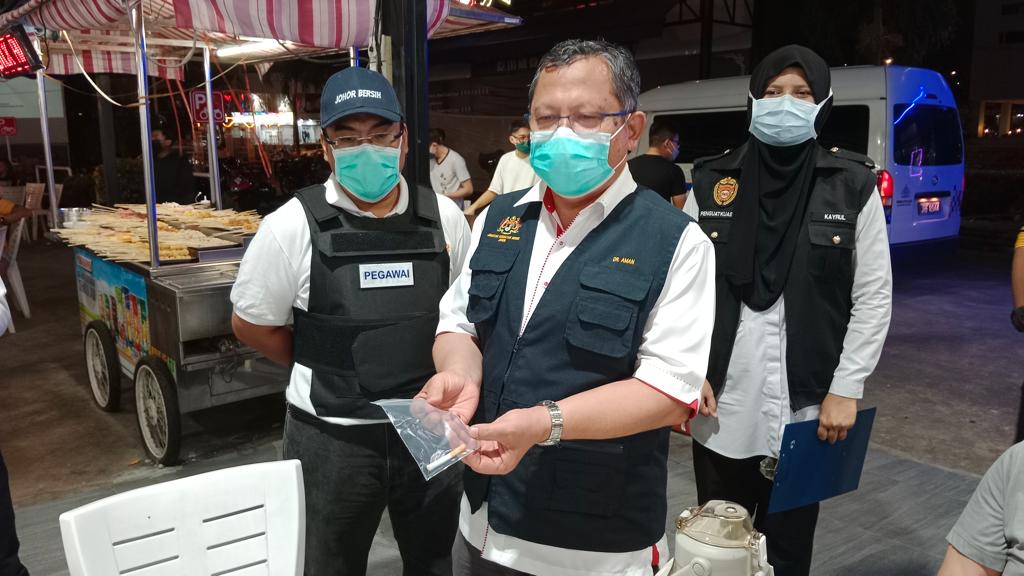 Aman menunjukkan puntung rokok yang dibuang di kedai-kedai makan. - Gambar oleh Izlaily Nurul Ain Hussein