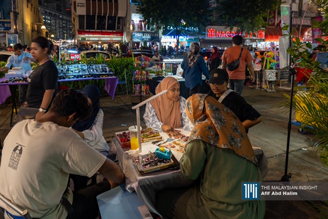 Seorang pelanggan mendapatkan khidmat pendandan bagi menghiasi tangannya dengan inai.