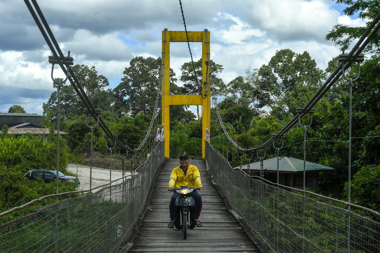 Penduduk menggunakan jambatan gantung bagi menyeberangi sungai untuk melakukan aktiviti harian di Pekan Engkilili. - Gambar Bernama