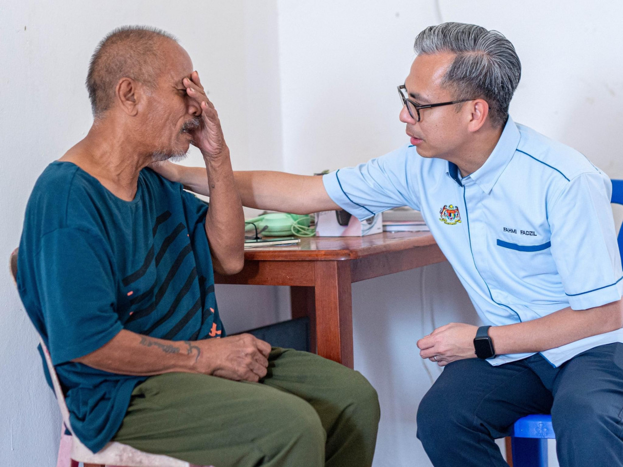 Fahmi Fadzil (kanan) mententeramkan Ross Ariffin yang tidak dapat menahan kesedihan - gambar Facebook