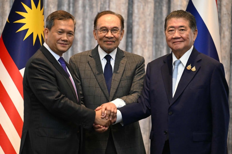 Anwar Ibrahim (tengah) bersama Perdana Menteri Kemboja, Hun Manet (kiri) dan Pemangku Perdana Menteri Thailand, Phumtham Wechayachai berjabat tangan selepas mesyuarat bersama mengenai gencatan senjata antara Thailand dan Kemboja di Putrajaya - Gambar AFP