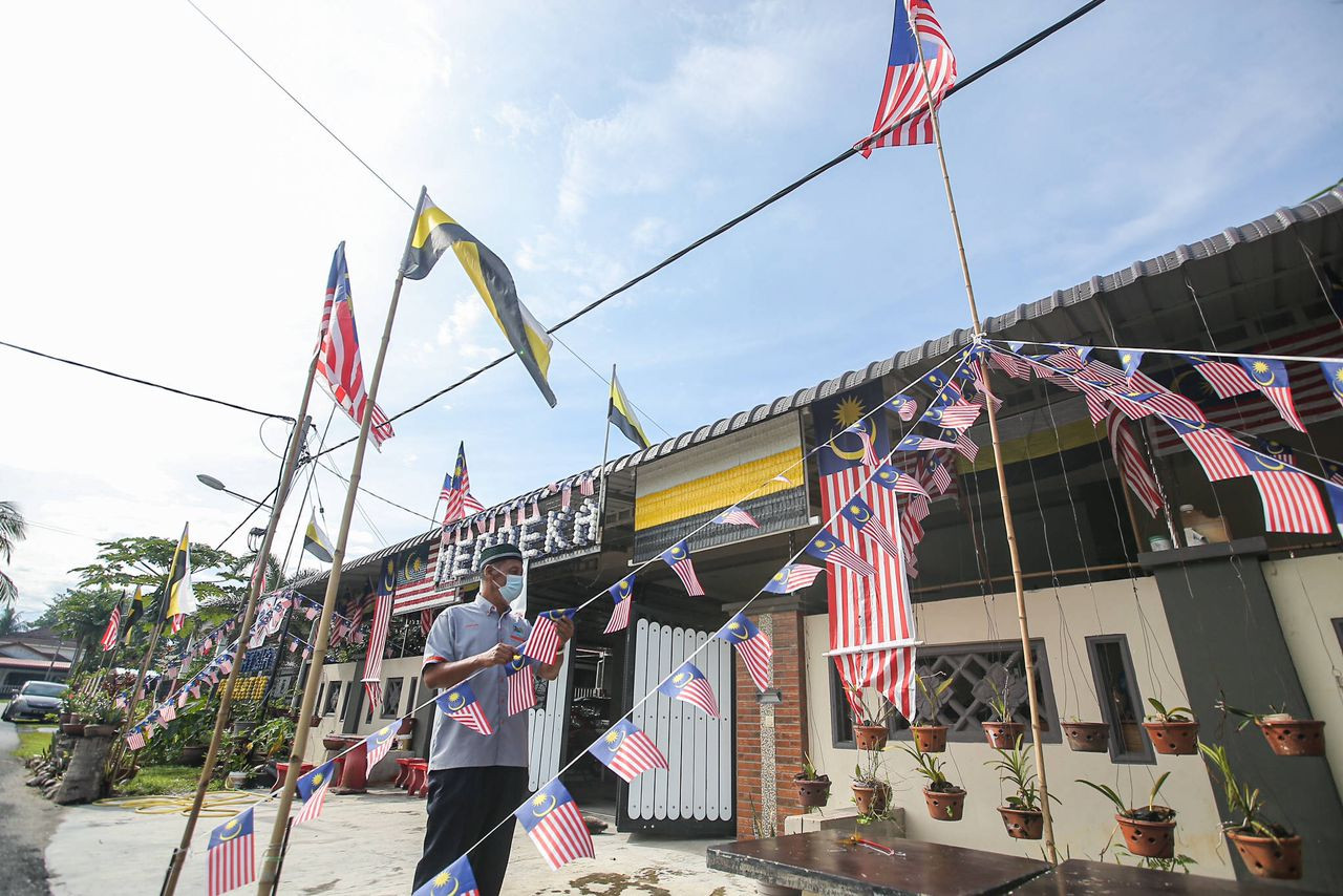 Jamaludin memasang Jalur Gemilang di hadapan rumahnya.