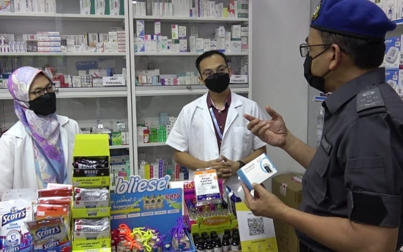 Pengarah (Bahagian Penguatkuasaan) KPDNHEP, Azman Adam (kiri) melakukan pemantauan penjualan kit ujian kendiri COVID-19 di sebuah farmasi di Temerloh, petang semalam.