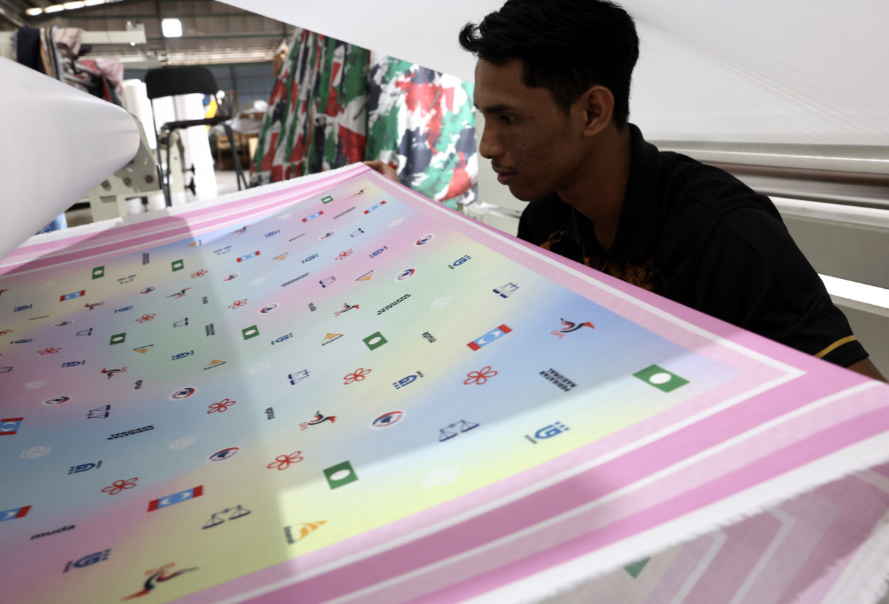 Penyelia Pembuatan Tudung Kekaboo Muhammad Nor Adha Nordin, 23, membantu dalam penghasilan jualan tudung bermotifkan logo parti politik. - Gambar Bernama