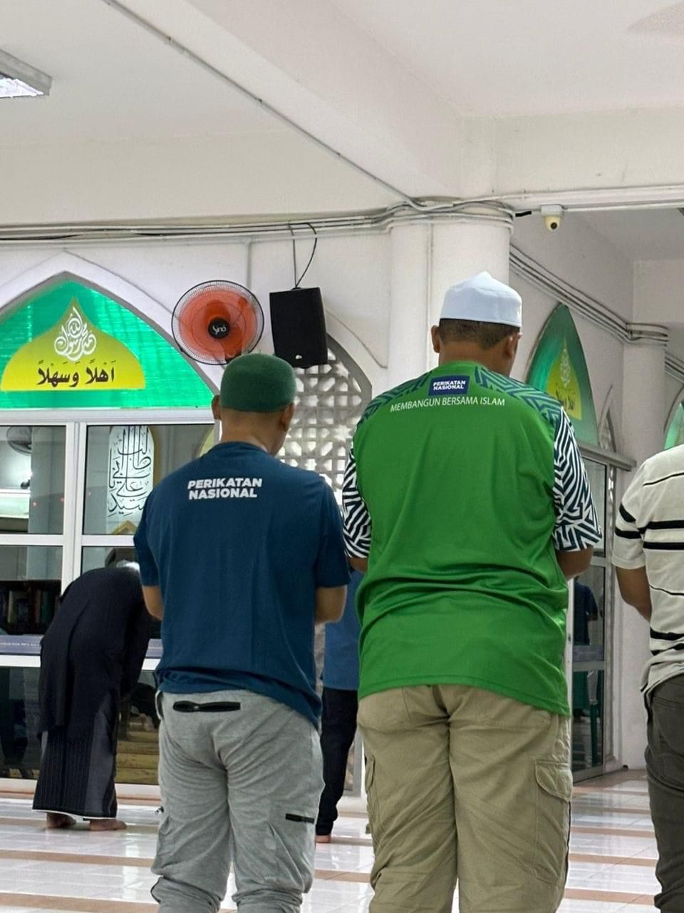 Dua jemaah yang dibenarkan menunaikan solat walaupun mengenakan baju berlogo PN dan PAS - Gambar Facebook