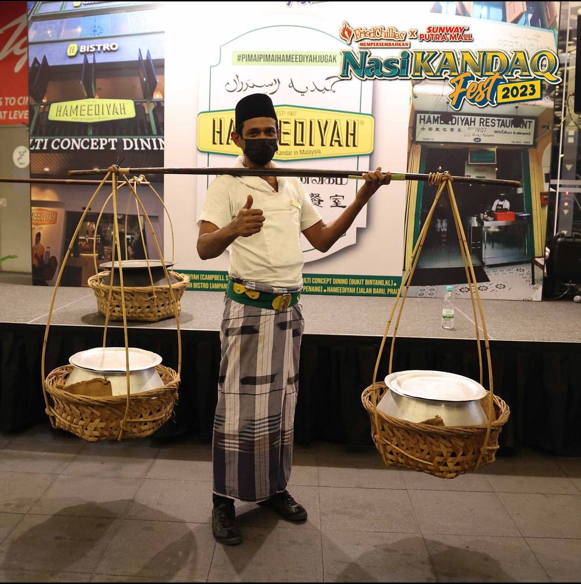 Salah seorang mamu di Nasi Kandaq Festival sedang mengandar peralatan tradisional yang membawa nasi kandar suatu ketika dahulu.