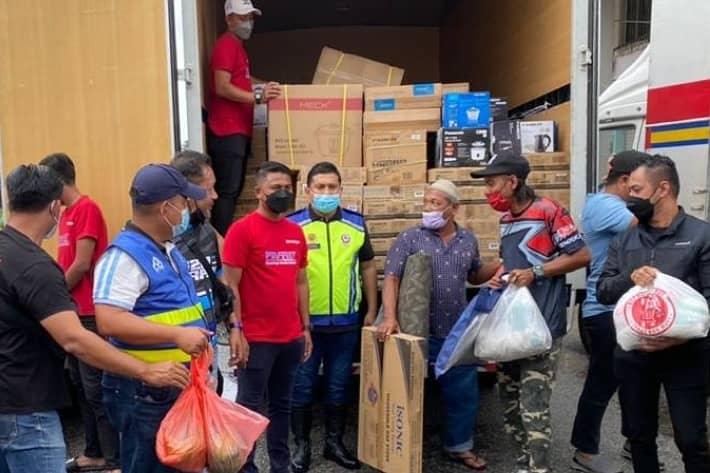 Mohd Khairul Faiz (empat dari kanan) membantu mengagihkan barangan elektrik kepada penduduk terjejas banjir di Taman Inderapura, di sini, hari ini.