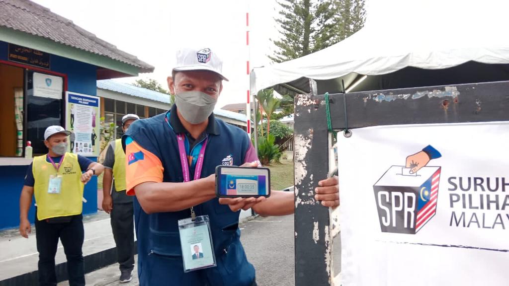 Rodyisnansyah menunjukkan jam tepat 6 petang sebelum menutup pagar pusat mengundi.