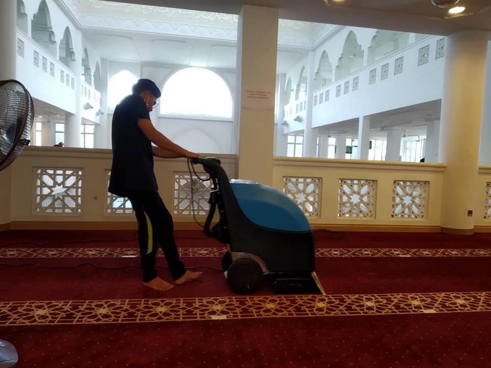 Seorang pekerja sedang membersihkan karpet di Masjid At-Taqwa Kampung Paroi, Negeri Sembilan. - Gambar dari Facebook