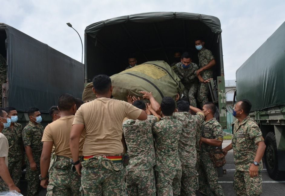 Anggota TUDM memunggah kelengkapan daripada lori. \