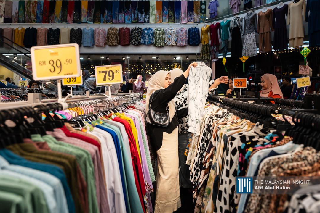 Seorang wanita 'membelek' pakaian yang ditawarkan sebelum membuat pembelian.