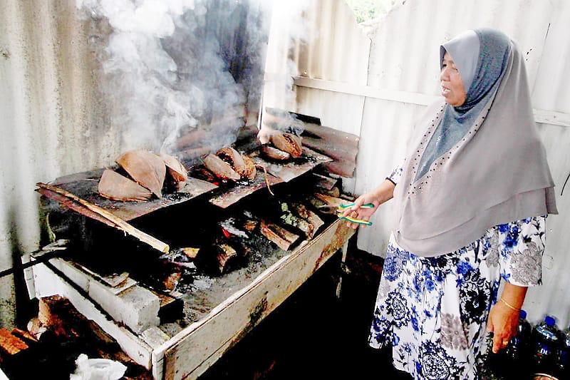 Membakar bahulu secara tradisional menggunakan 'oven' zink dan api sabut. Kredit Media Permata.