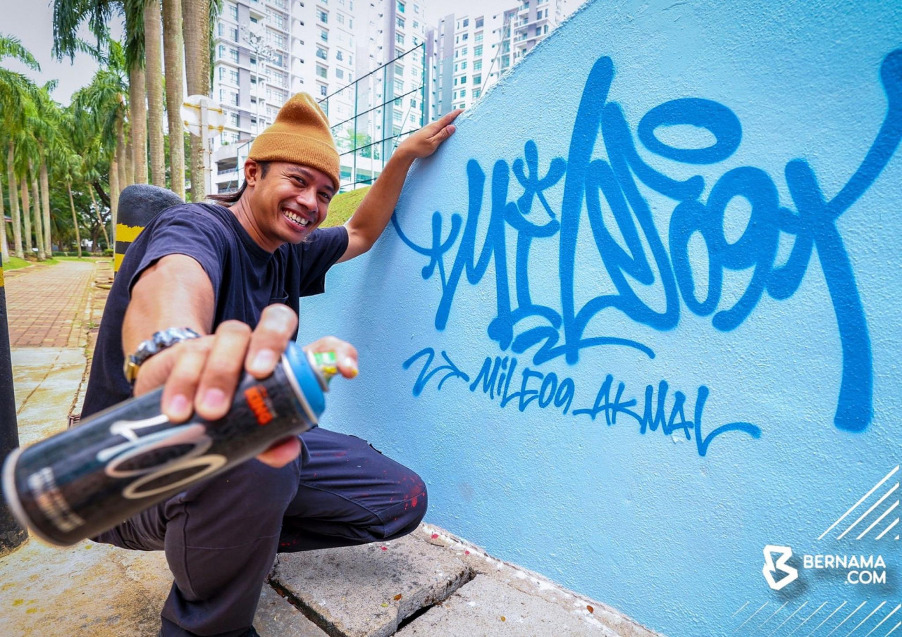 Muhammad Fakhrul Akmal Shamsurrijal menyiapkan lakaran grafiti pada dinding di laluan pejalan kaki di Presint 8 baru-baru ini. gambar BERNAMA